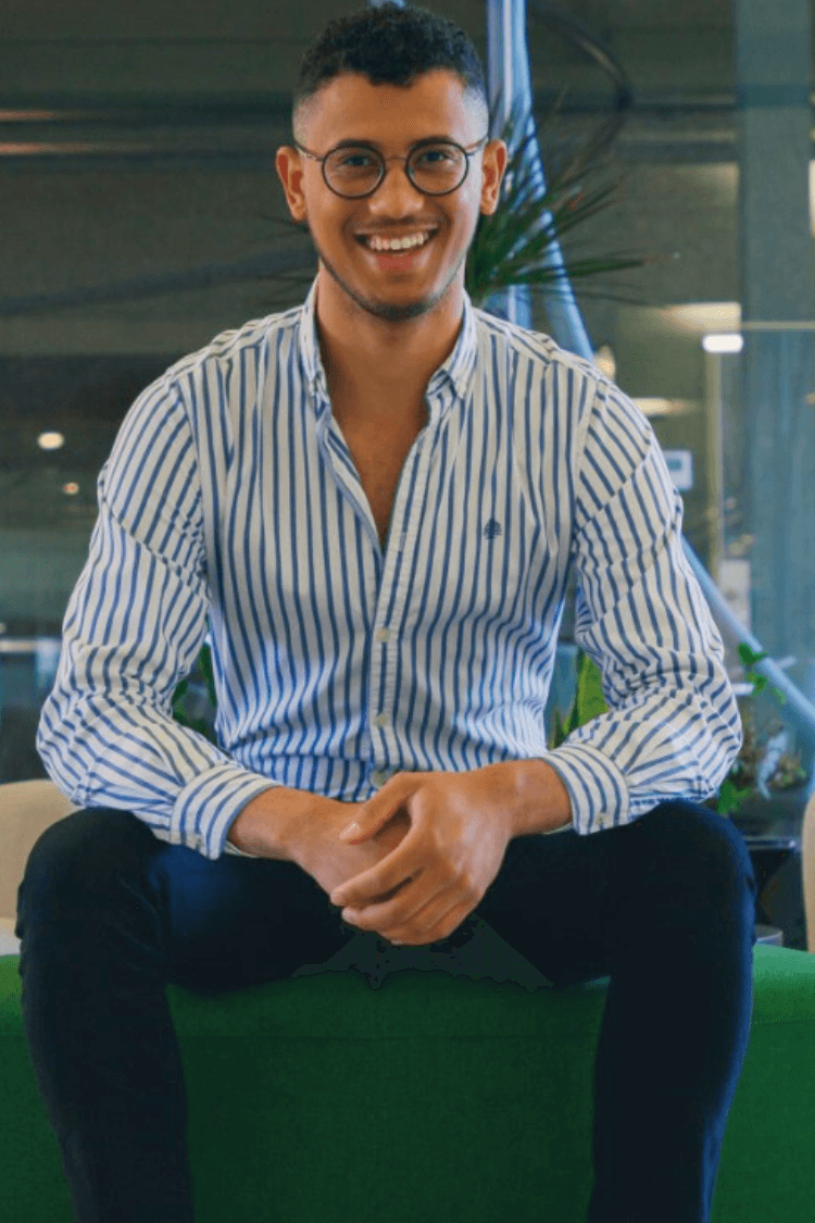 A man sat on a bench wearing a blue shirt. 