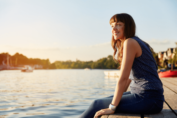 Une femme est assise sur le quai, les jambes par-dessus le bord.