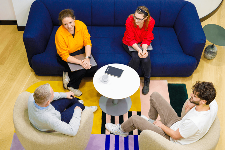 Een groep van vier casual geklede collega's zat te kletsen op de bank.