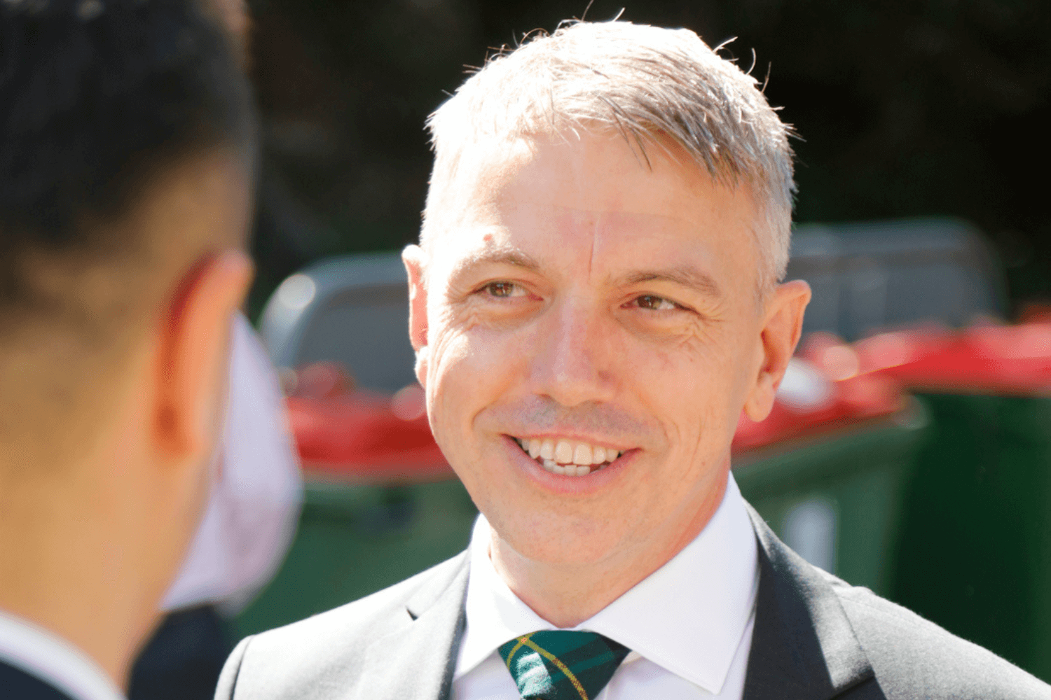 一个身穿白色短衣、黑色夹克、系着绿色领带的男人。