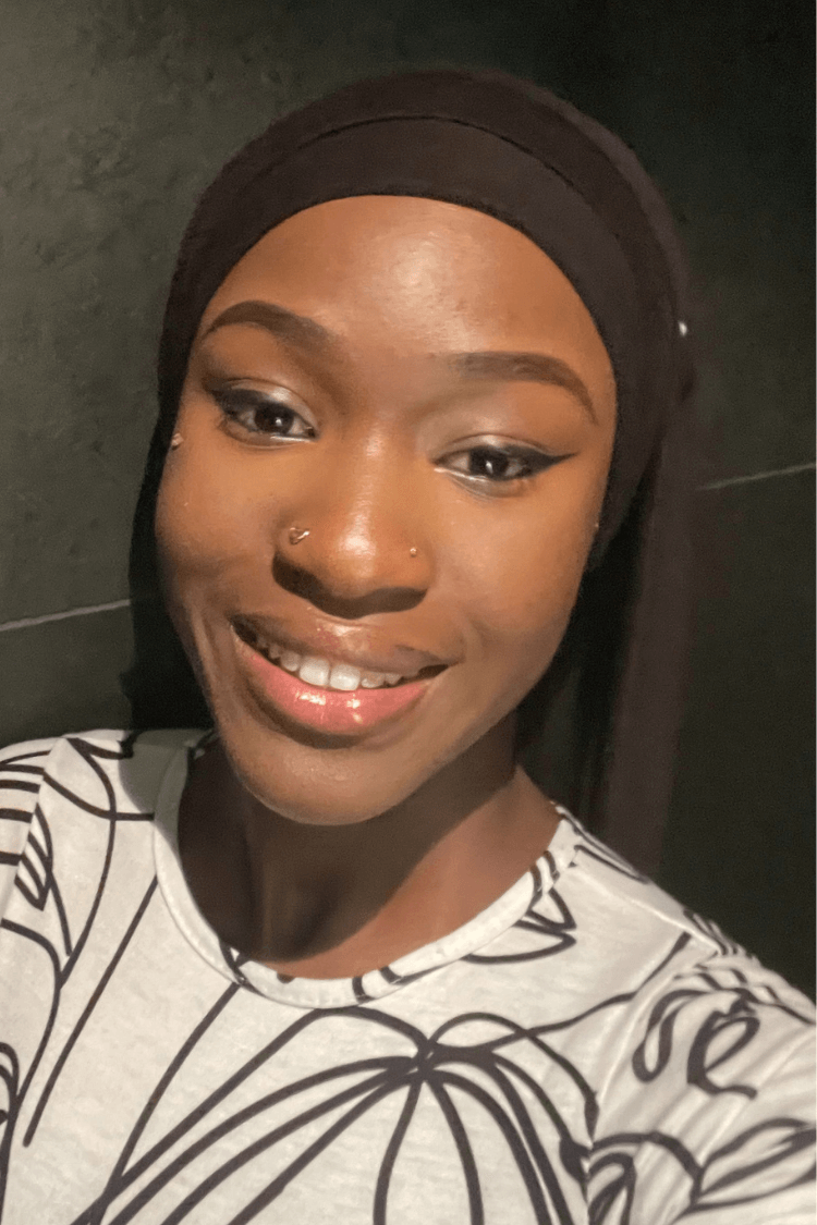 一位戴着黑色发箍的年轻女孩。她身穿一件带有黑色线形图案的白色上衣。